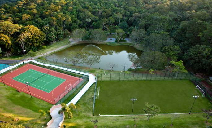 Quadra de tênis e campo de futebol próximos a um lago